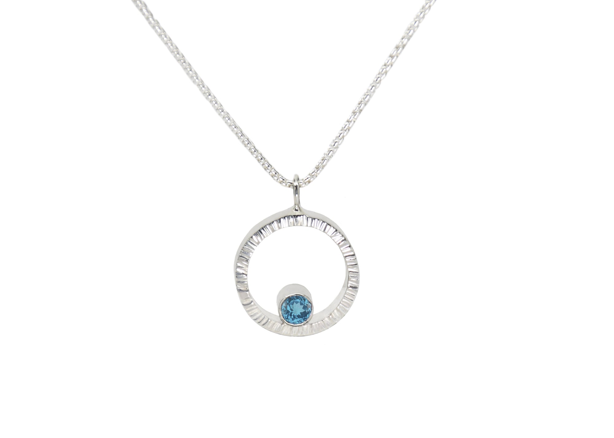 A sterling silver hammered circle pendant with Swiss blue topaz
