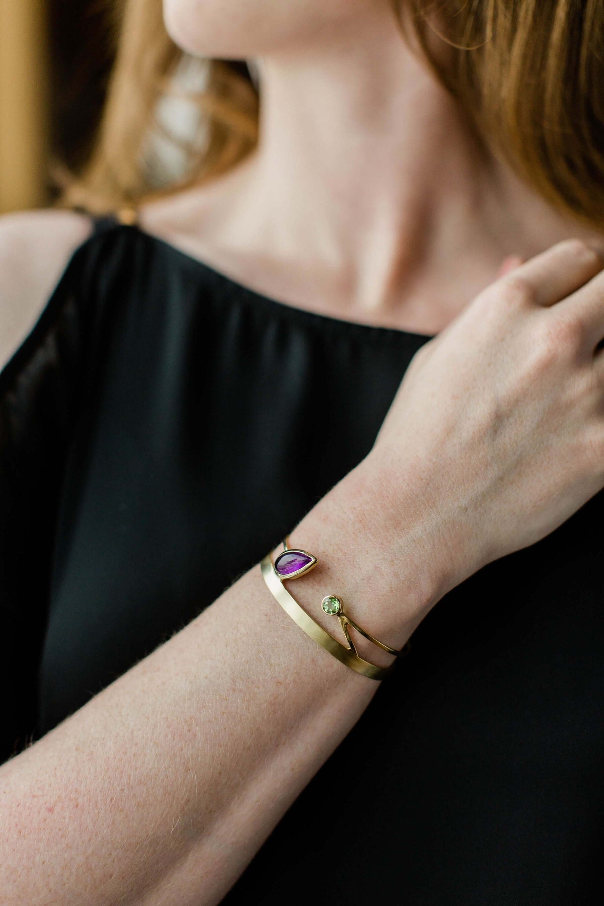 A model wears a 14k gold version of the  silver amethyst cuff bracelet with peridot
