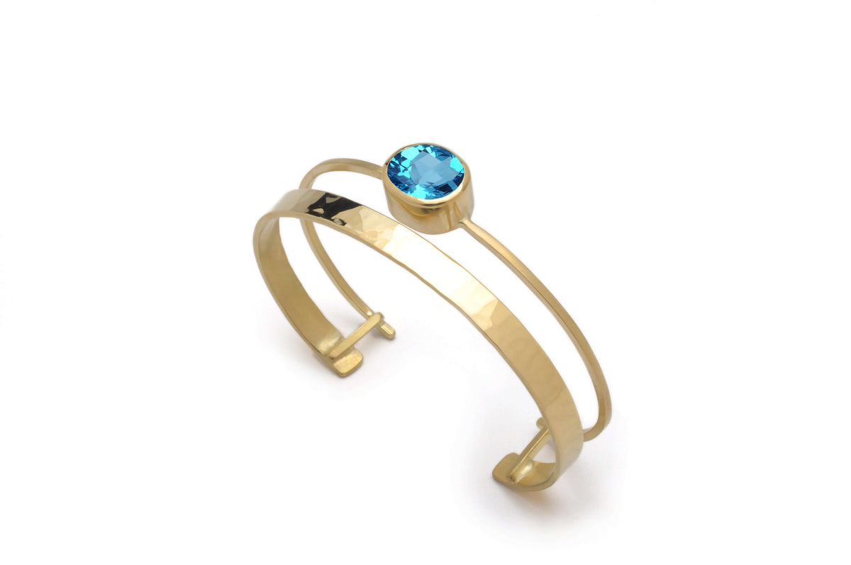 a 18k gold cuff bracelet with swiss blue topaz