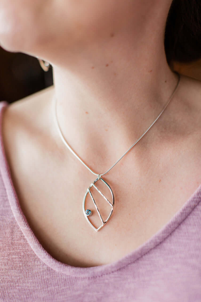 A model wears sterling silver leaf earrings with sky topaz
