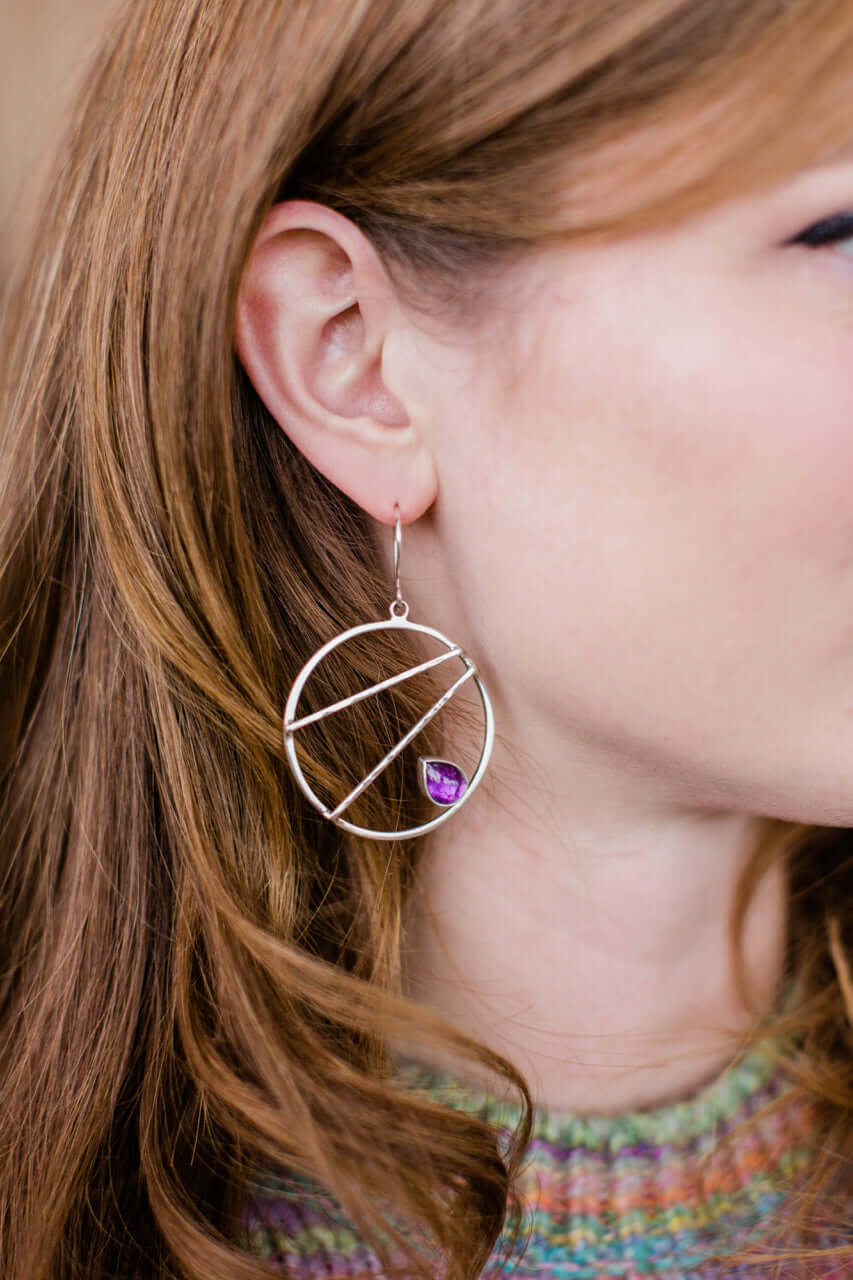 A model wears Sterling silver crossbar hoop earrings with amethyst