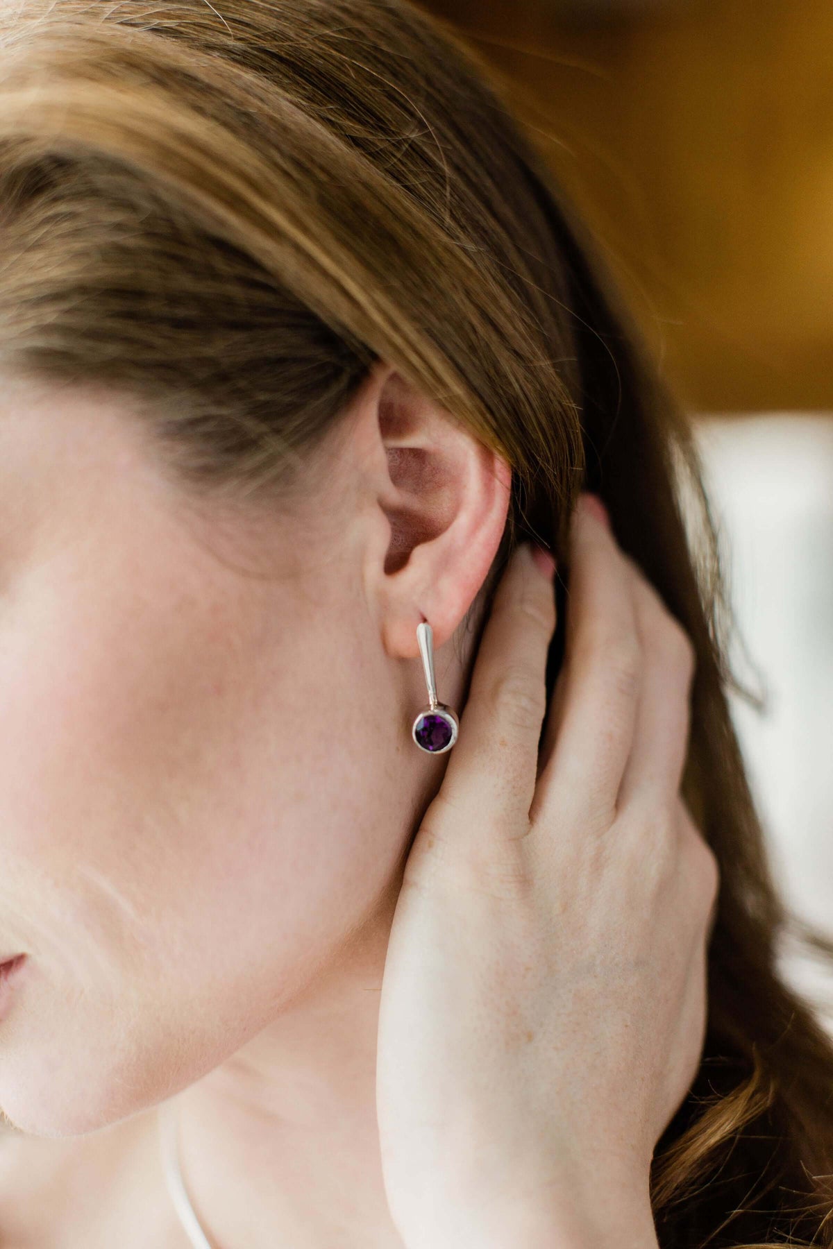 A model wears sterling silver and purple amethyst drop earrings