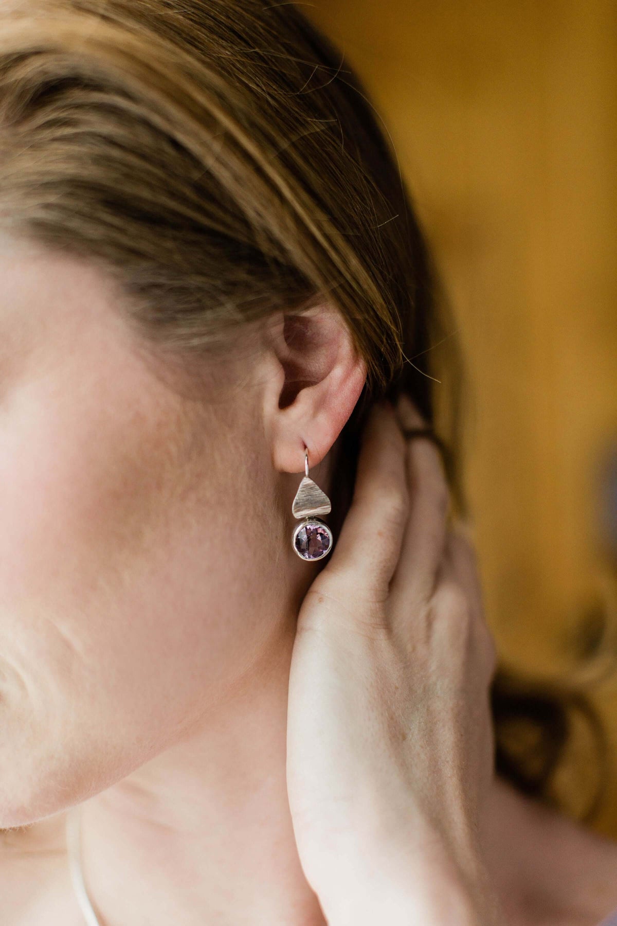 A model wears a pair of sterling silver and pink amethyst flora drop earrings
