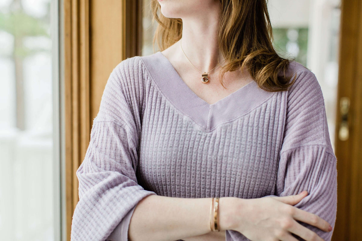A woman wears a 14k gold pink amethyst pendant on a gold chain