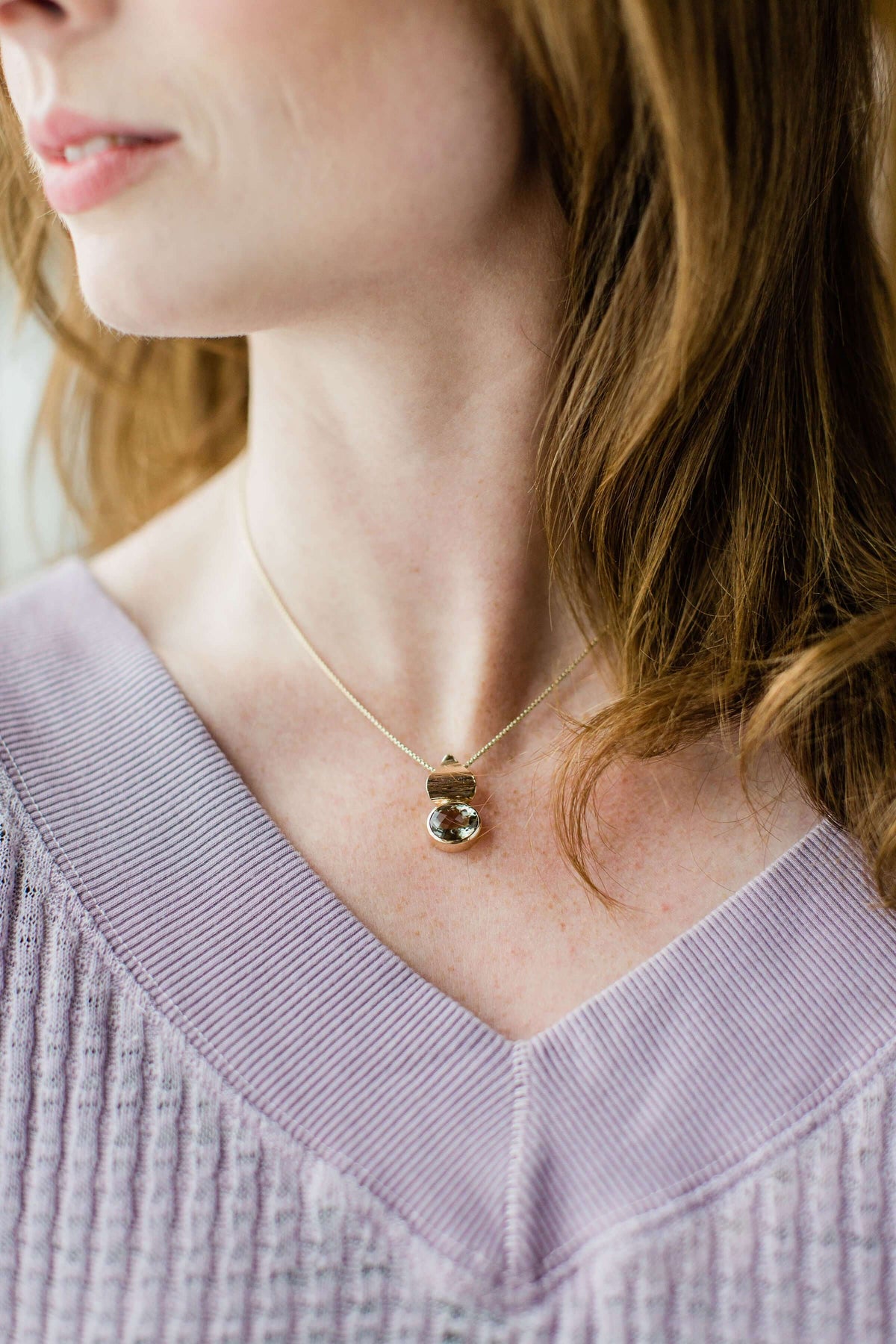 a woman wears a purple sweater with prasiolite pendant gold with a 14k gold chain