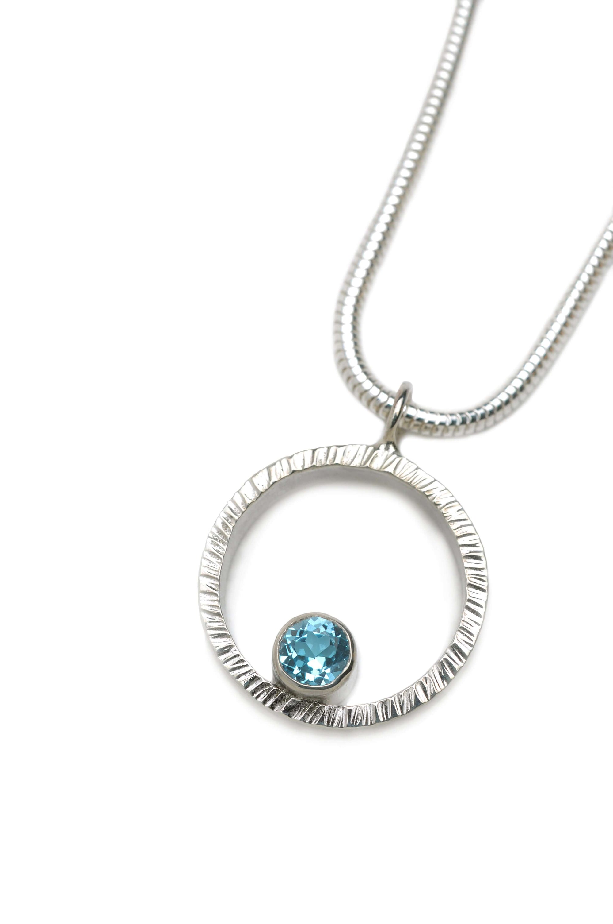 A hammered circle pendant necklace with Swiss blue topaz