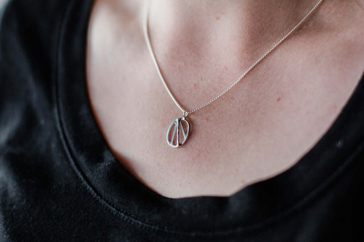A woman wears a black shirt and a sterling silver oval pendant on silver chain