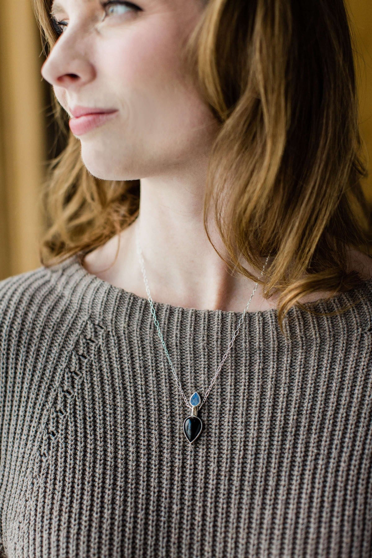 A black onyx necklace with Swiss blue topaz and sterling silver worn by a model