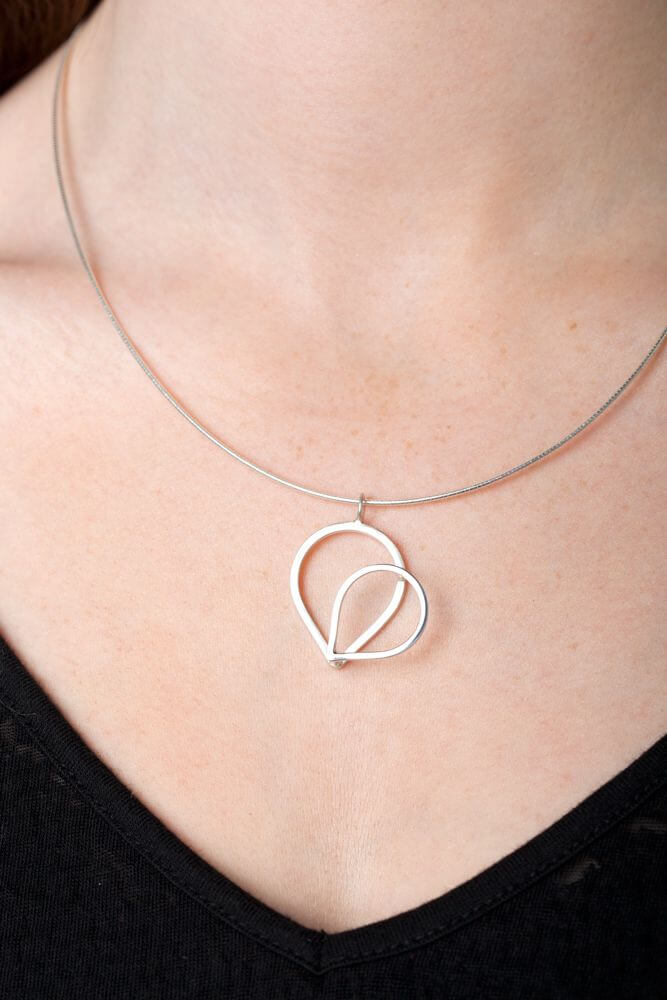 a 3D handmade silver heart necklace on silver chain