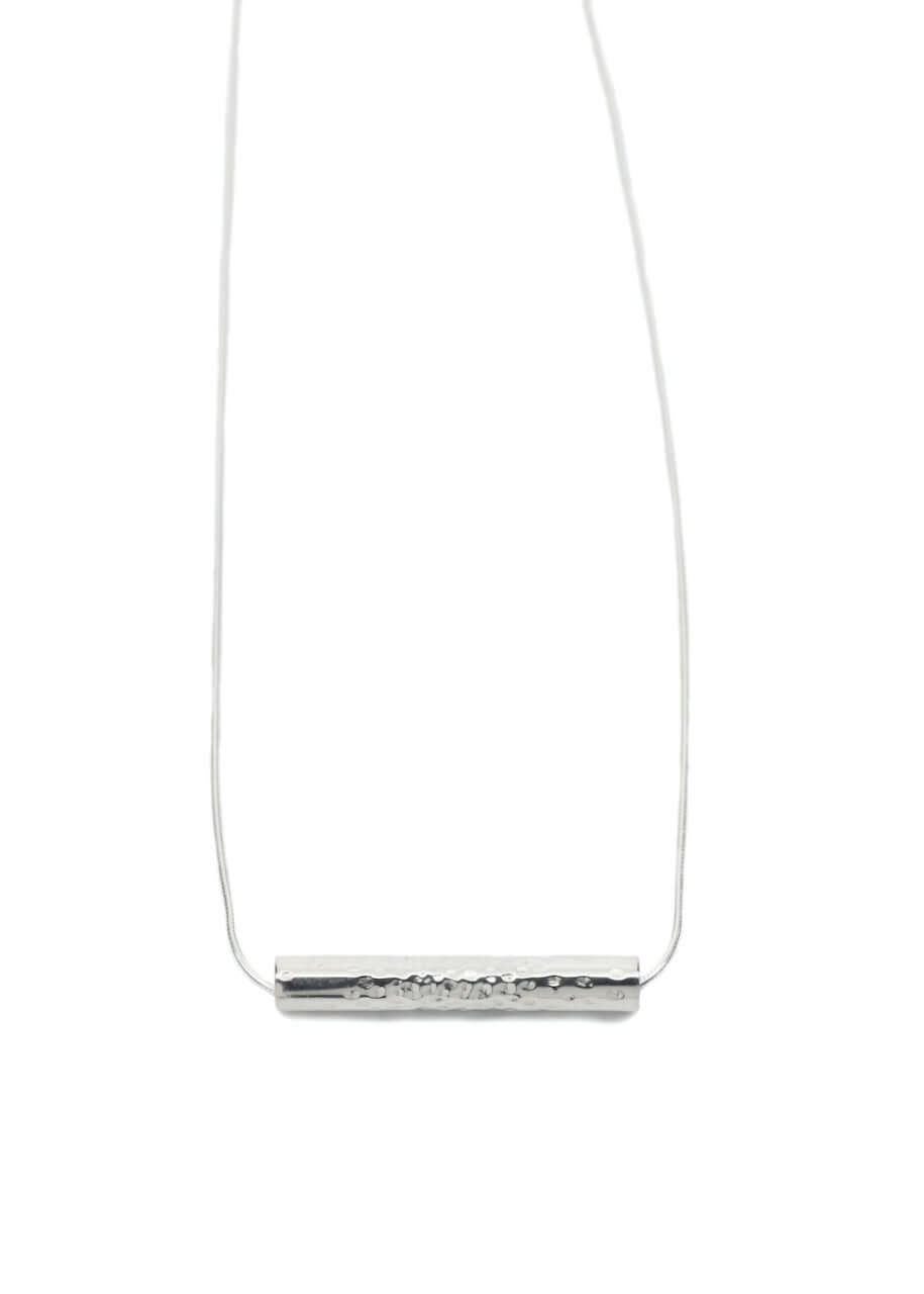 A handmade silver tube necklace with dotted texture on a silver chain
