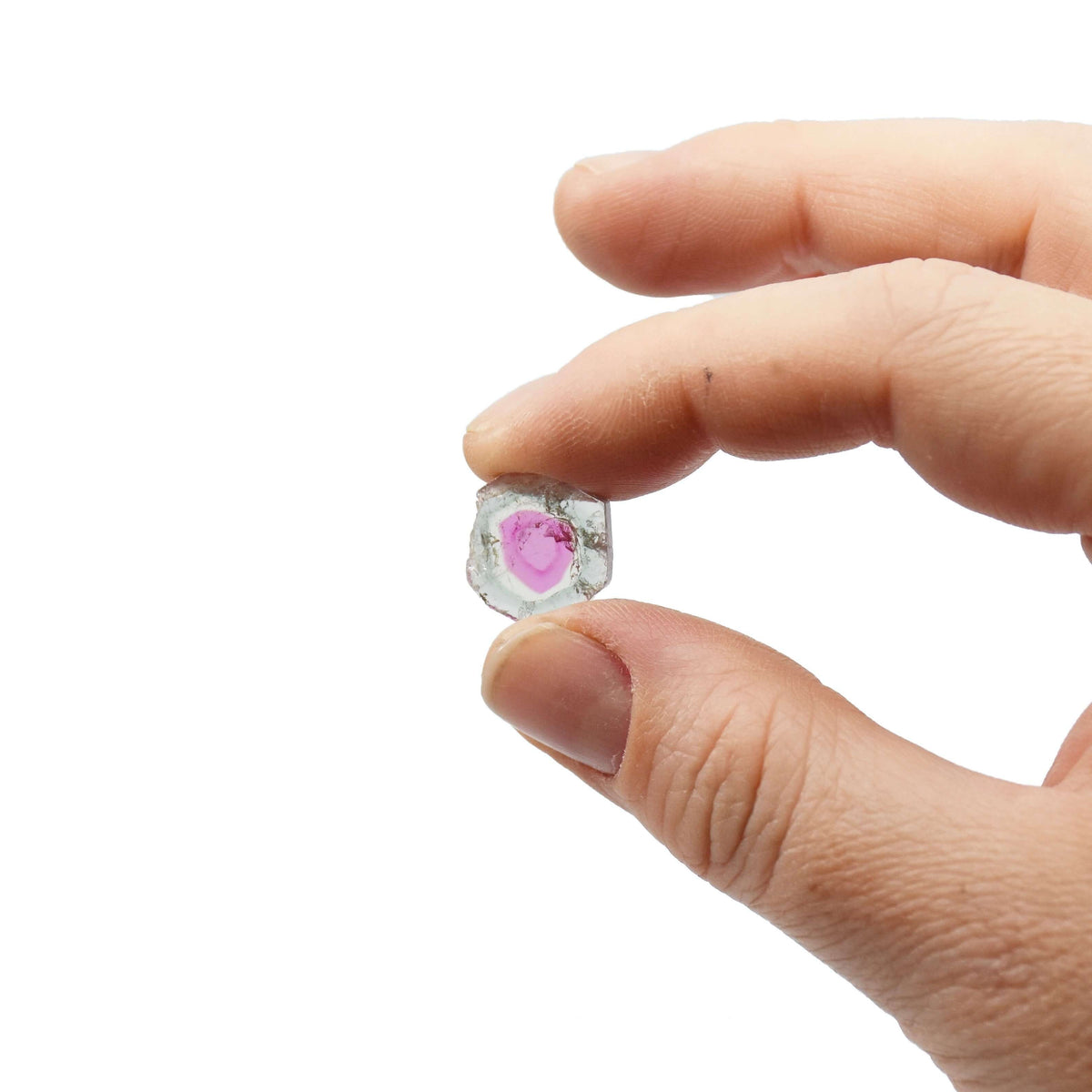 A hand holds a thin watermelon tourmaline slice for custom fine jewelry.
