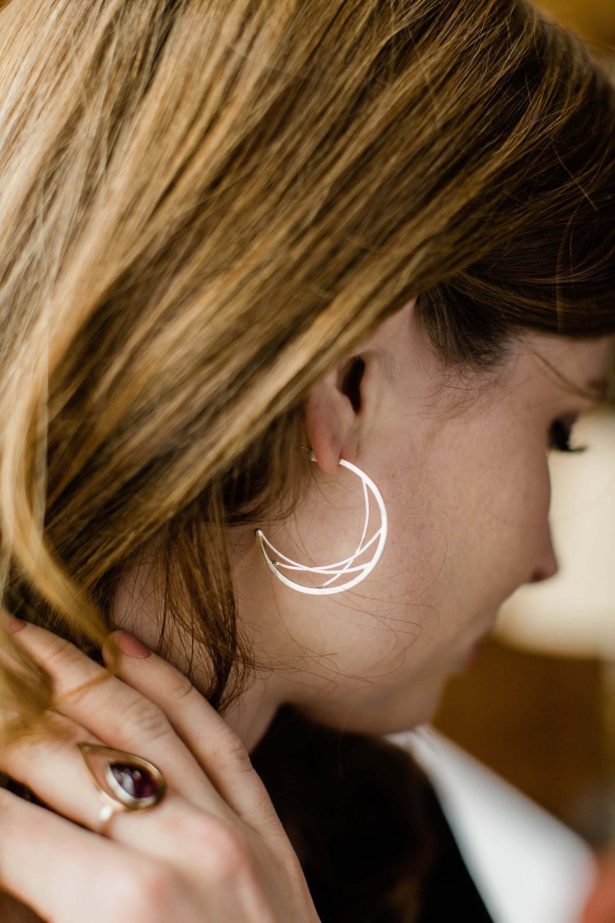 A model wears silver crescent hoop earrings