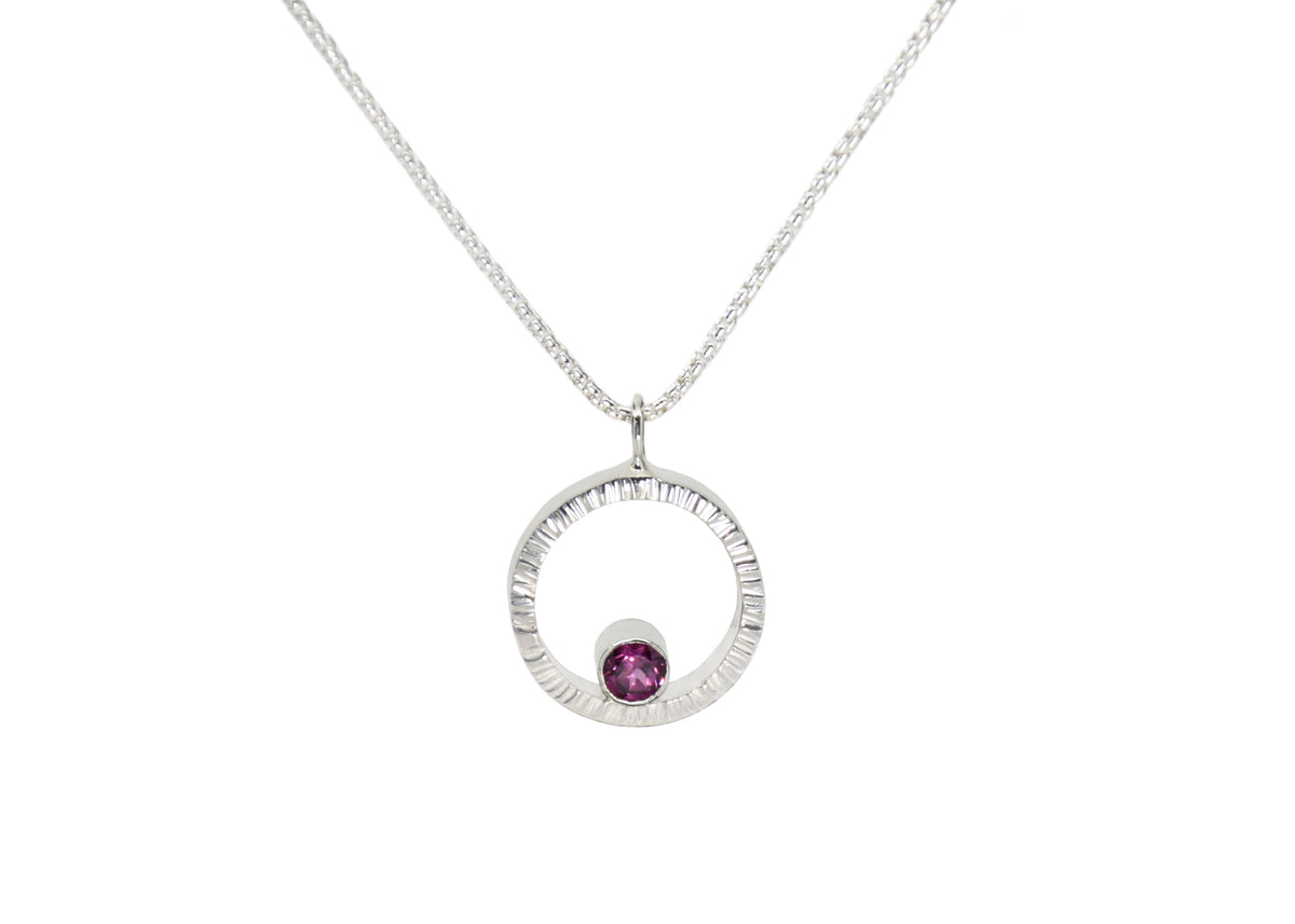 A sterling silver hammered circle pendant with garnet