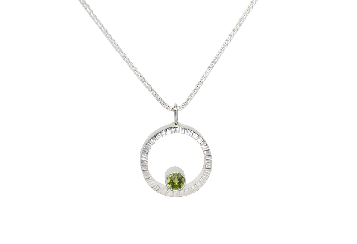 A sterling silver hammered circle pendant with peridot