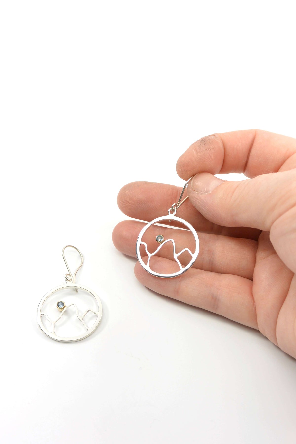 a hand holds a pair of mountain earrings in sterling silver