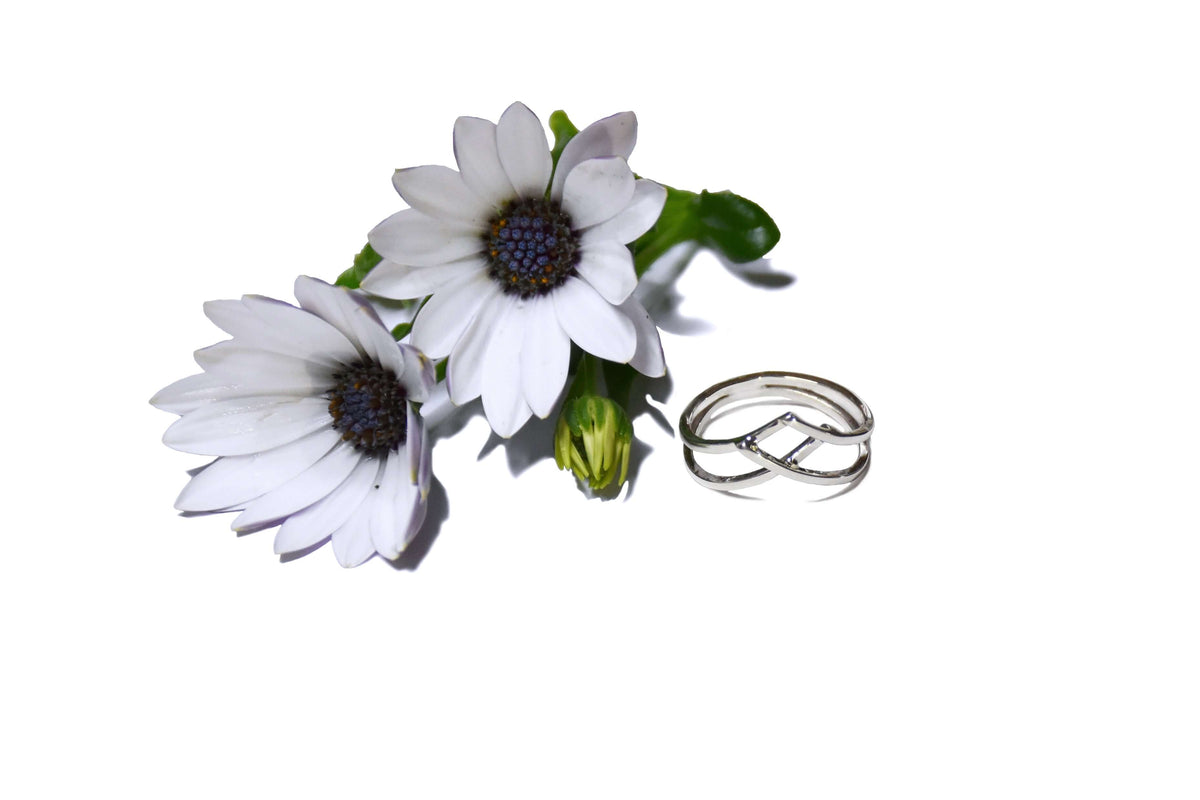 A woven silver ring next to white flowers
